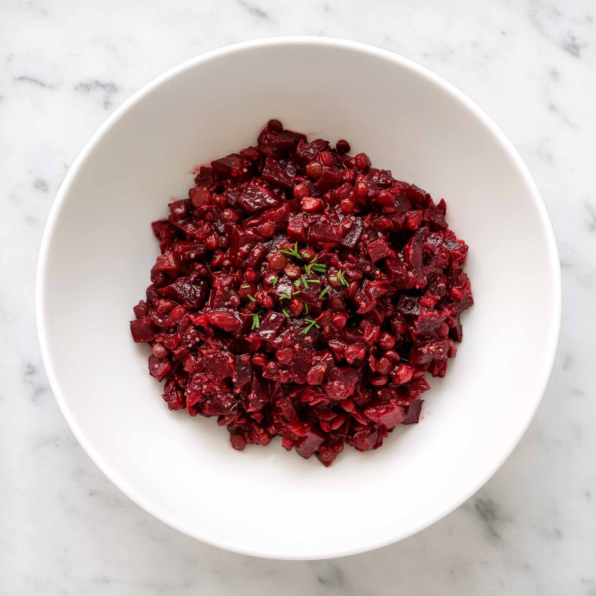 Beetroot and lentil salad in a white bowl on a marble surface.