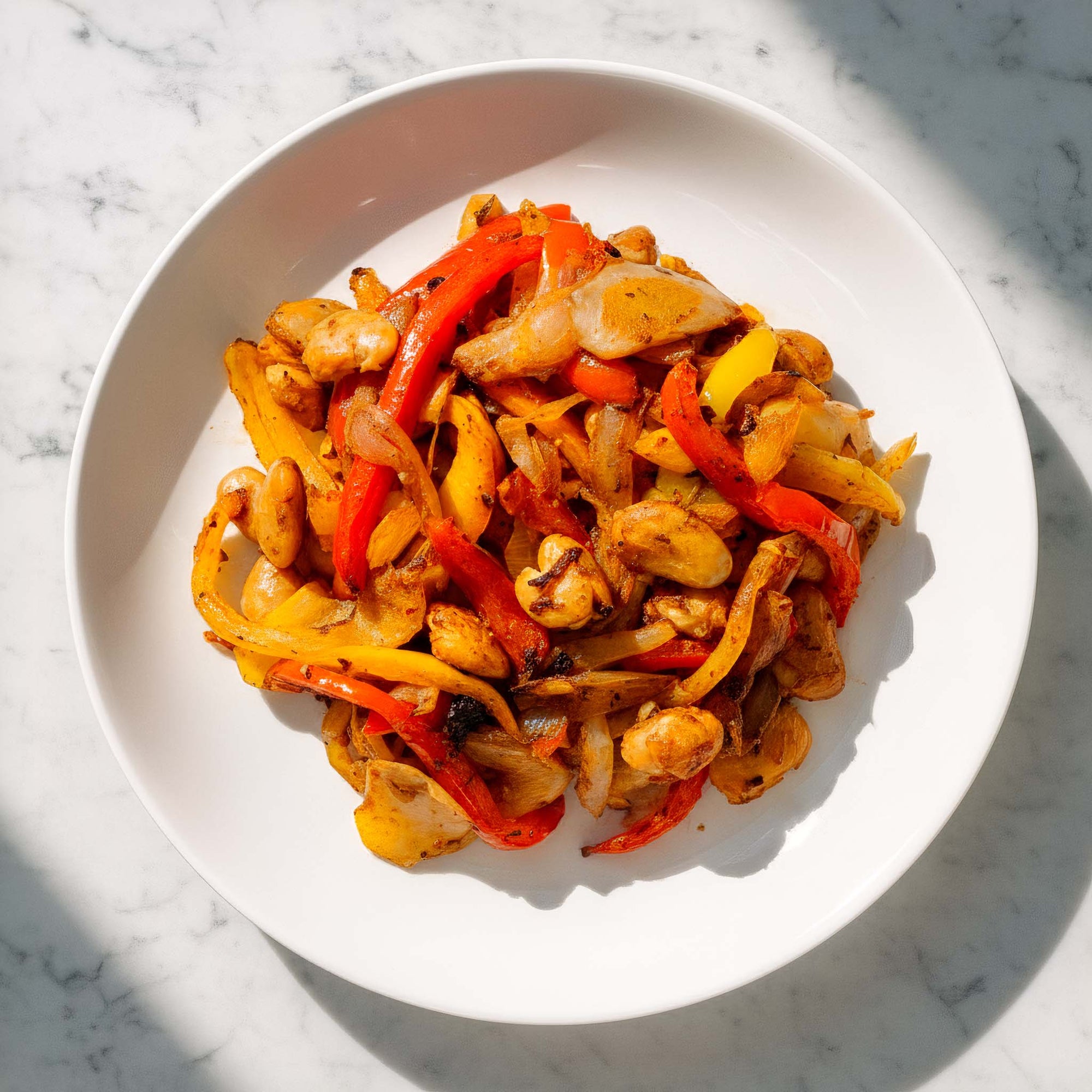 Close-up of plated roasted peppers and onions and butter beans, seasoned with Tex-Mex spices, on a marble surface.